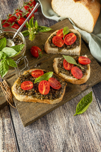 Homemade bruschetta with pesto sauce, fresh tomatoes on a wood background. Traditional italian appetizer or snack, antipasto. Copy space.