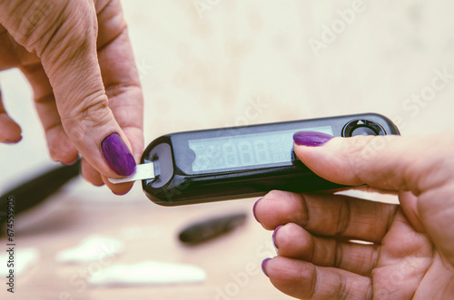 Close-up hands. Glucose meter and hands putting lancet into it