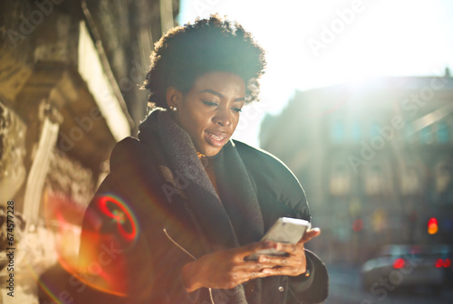 young black woman uses a smartphone on the street