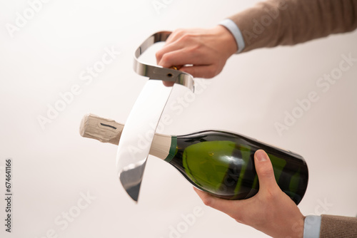 Well dressed man opening champagne bottle with champagne saber, studio environment.