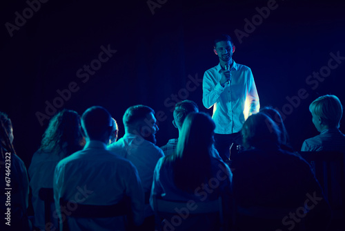 Young man, employee standing on stage during business conference, talking about success and strategies. Concept of business, education, partnership, coaching, entrepreneurship