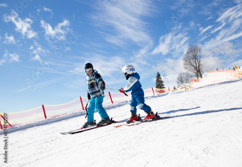 llittle boy learning to ski with his father during winter holidays in snowy mountains on a sunny cold day. Winter active walks with children. Seasonal joys with family, happy childhood. Frosty weather