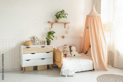 a cozy and bright children's room with a four-poster bed, a chest of drawers, a floor lamp and cute soft toys. light background