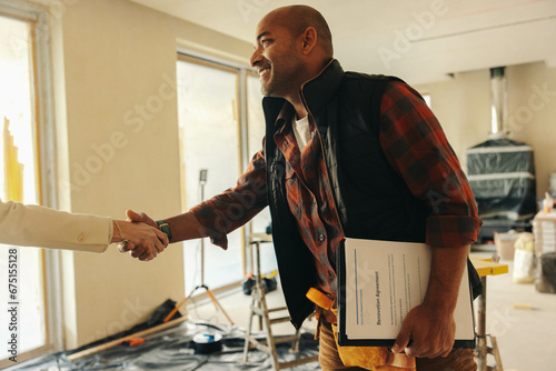 Professional contractor shakes hands with happy homeowner for interior renovation project