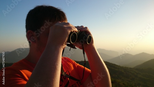 The guy looks into the binocular. Sunset on a mountain's view point in India. Maharashtra State. 