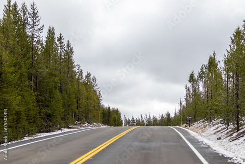 snow on road in the yellowstone mountains, Image shows the first signs of snowfall in Yellowstone national park with the forest background, October 2023