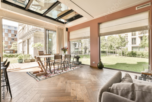 a living room with wood flooring and glass doors that open to the backyard area, which is covered in blinds