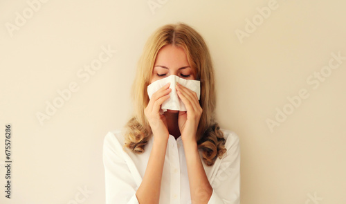 Sick exhausted caucasian young woman employee sneezing blow nose using tissue at home