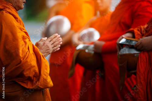 Buddhist monk holding alms bowl waitting for buddhism make merit by offering food and water at morning