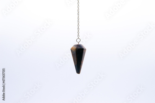 Tiger's eye crystal pendulum on chain isolated on white background.