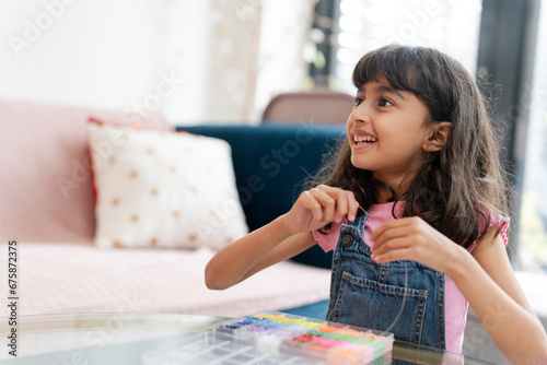 Little girl playing with beads in living room