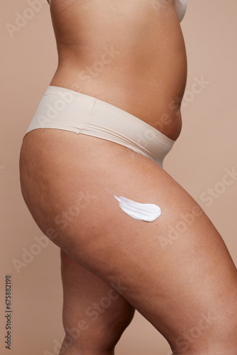 Studio shot of young woman using anti-cellulite cream