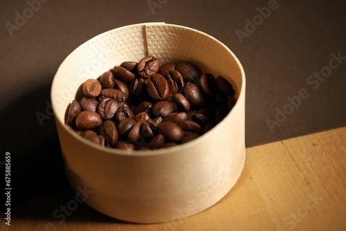 Beige wicker container filled with coffee beans on a wooden table