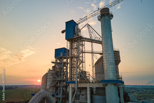 Cement plant with high factory structure and tower cranes at industrial production area. Manufacture and global industry concept