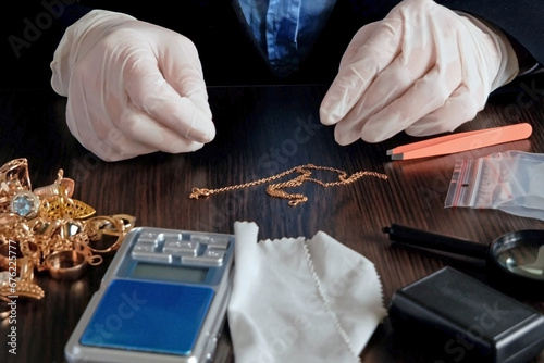 Pawnshop worker verify golden jewelry on many golden and silver jewelleries, scales and money background. Customers Buy and Sell Precious Metals, Jewels, Ancient Coins and Second Hand Appliances.