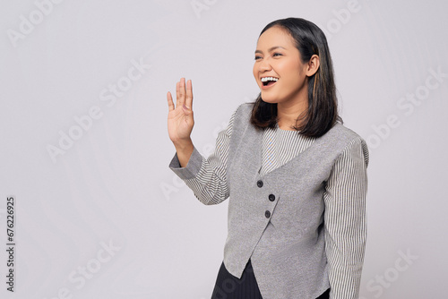 Smiling happy beautiful young Asian woman in casual clothes saying hello, showing hi gesture with waving hands with friendly expression isolated on white background. People lifestyle emotion concept