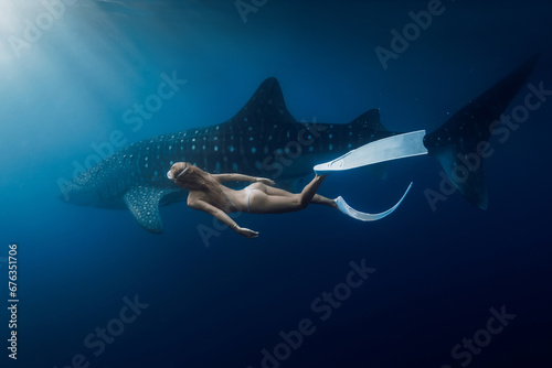 Underwater view of female freediver swimming with giant whale shark