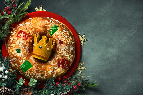 Top view of Roscon de reyes with cream and crown of the three wise men on a red plate with space for text. Kings day concept spanish three kings cake