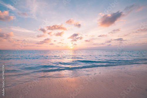Beautiful sunset horizon sea or ocean. Vibrant soft colors magic sunlight. Small clouds yellow golden sky, reflection of sun water sand on beach. Peaceful romantic vacation in tropical island paradise
