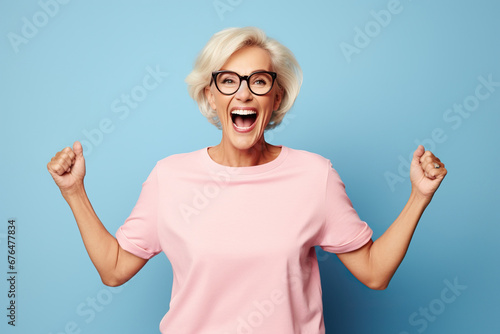 Elderly overjoyed excited fun cool woman 50s years old she wears pink undershirt casual clothes look camera spread hands isolated on plain pastel light blue background studio Lifestyle concept