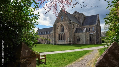 Pluscarden Abbey Monastery with a cloudy blue sky in the background in Pluscarden, Scotland