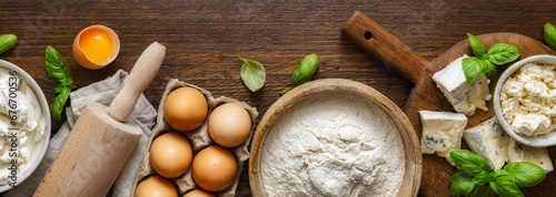 Raw ingredients for cooking Italian ravioli with various cheeses and spinach on wooden table top view