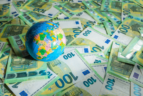 Globe map over many money bills with background of 100 euros