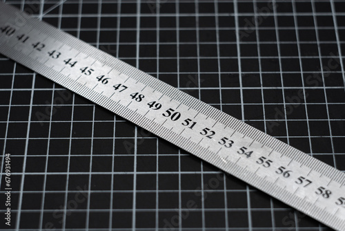 A metal ruler on the mark of 80 centimeters against the background of the grid on the cutting mat.