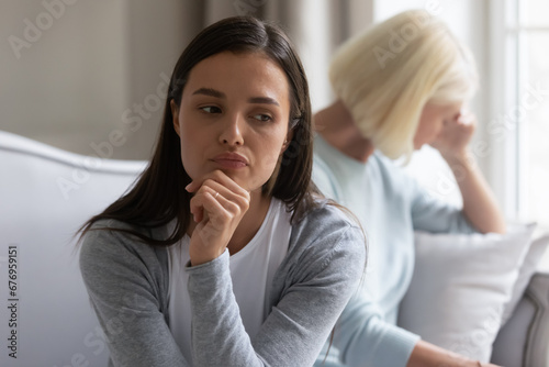 Annoyed selfish young woman ignoring unhappy mature mother after quarrel close up, parent and child, generations conflict, senior mum and grown daughter sitting back to back, misunderstanding