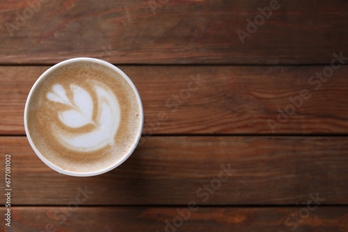 Coffee to go. Paper cup with tasty drink on wooden table, top view. Space for text