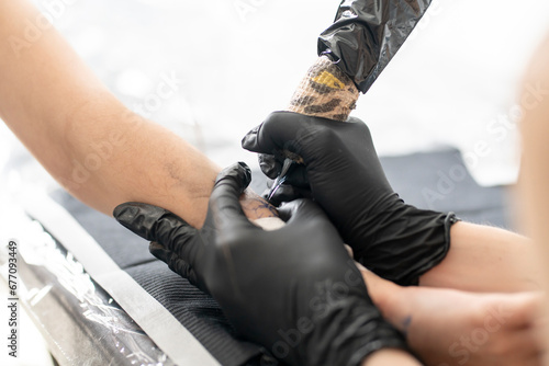 close up female tattoo master making a new flower tattoo using modern new machine