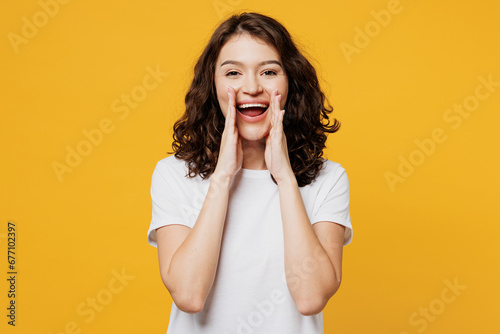 Young promoter fun woman she wear white blank t-shirt casual clothes scream sharing hot news about sales discount with hands near mouth isolated on plain yellow orange background. Lifestyle concept.