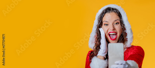 young woman in santa claus costume isolated using mobile phone or smartphone