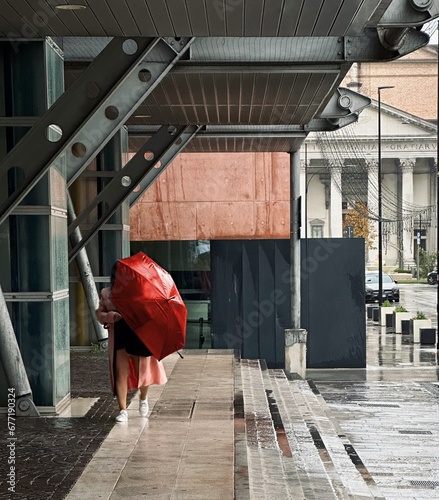Ragazza con ombrello rosso sotto la pioggia che passeggia