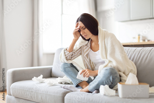 Seasonal Flu Concept. Sick Young Woman Covered In Blanket Sitting On Couch