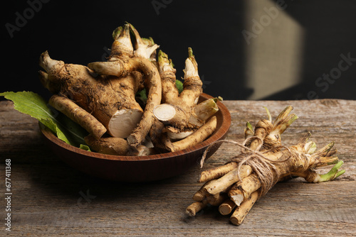 Fresh horseradish roots on wooden table, closeup