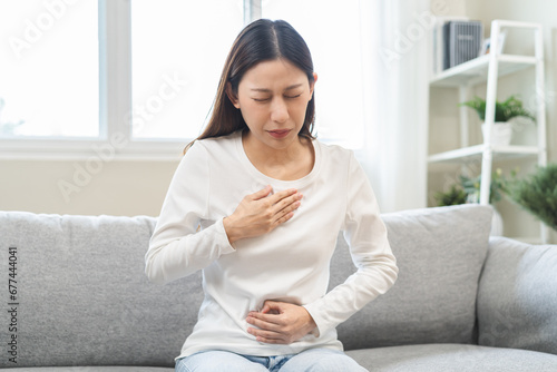 Acid reflux disease, suffer asian young woman have symptom gastroesophageal, esophageal, stomach ache and heartburn pain hand on chest from digestion problem after eat food, Healthcare medical concept