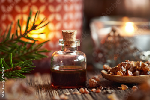A bottle of myrrh essential oil with spruce branches and candle at Christmas