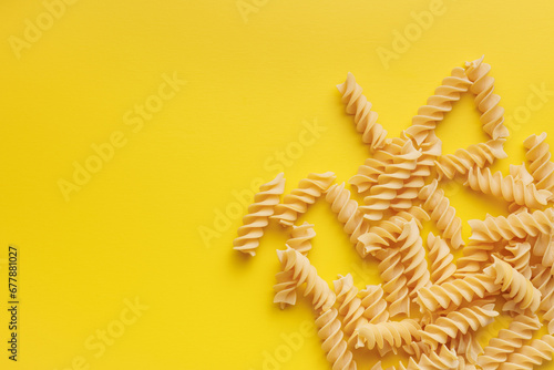Uncooked fusilli pasta. Uncooked italian pasta on yellow background.