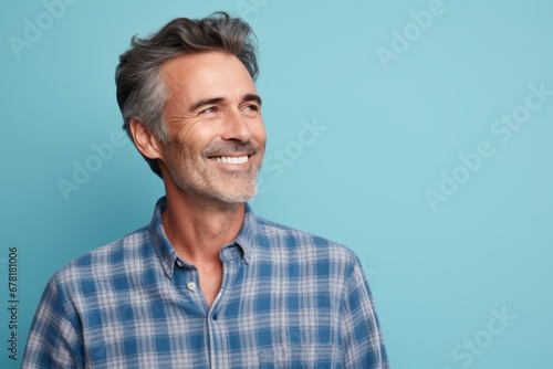 Portrait of a glad man in his 50s wearing a comfy flannel shirt against a pastel blue background. AI Generation
