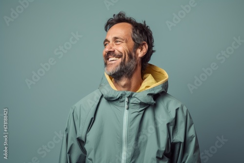 Portrait of a jovial man in his 40s wearing a functional windbreaker against a pastel gray background. AI Generation