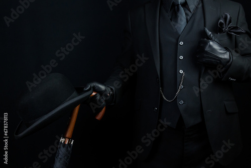 Portrait of British Businessman in Dark Suit Holding Umbrella and Bowler Hat. Mafia Hitman or Gangster.