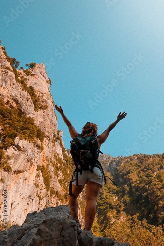 Vertical shot of a female hiker in shorts with a backpack posing on the mountains