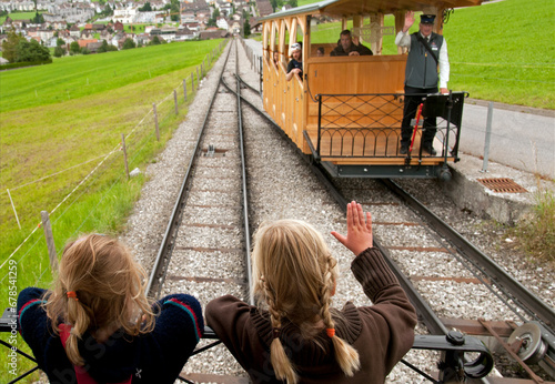 Stans, Nidwalden, Switzerland, Europe - funicular operator waves to two little girls, wooden retro train connects Stans town with change station leading to the top of Stanserhorn
