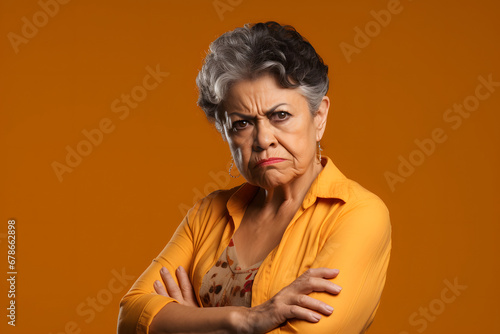 skeptic scowl senior Latin American woman, head and shoulders portrait on orange background. Neural network generated photorealistic image