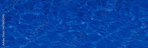 Transparent blue colored clear water surface texture with splashes. Water background, ripple and flow with waves. Blue water shinning. Sea, ocean surface. Overhead top view. Flat lay design.