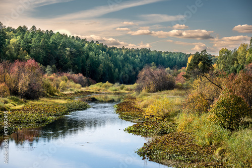 A winding river in the middle of the forest on an autumn day.