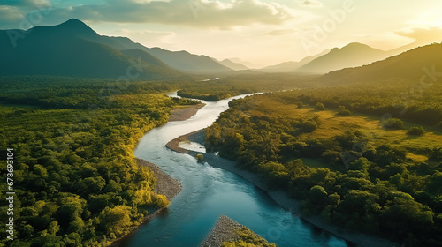 Beautiful natural scenery of river in tropical green forest with mountains in background at sunset, aerial view