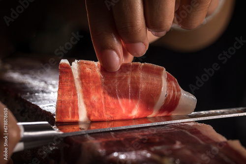 Jamón ibérico de bellota español. Cortador de jamón ibérico cortando a mano loncha para degustar. Típica loncha de jamón ibérico de gran calidad con sus vetas y grasa.