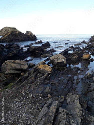 Vertical closeup shot of a rocky shore washed by the waters of a sea